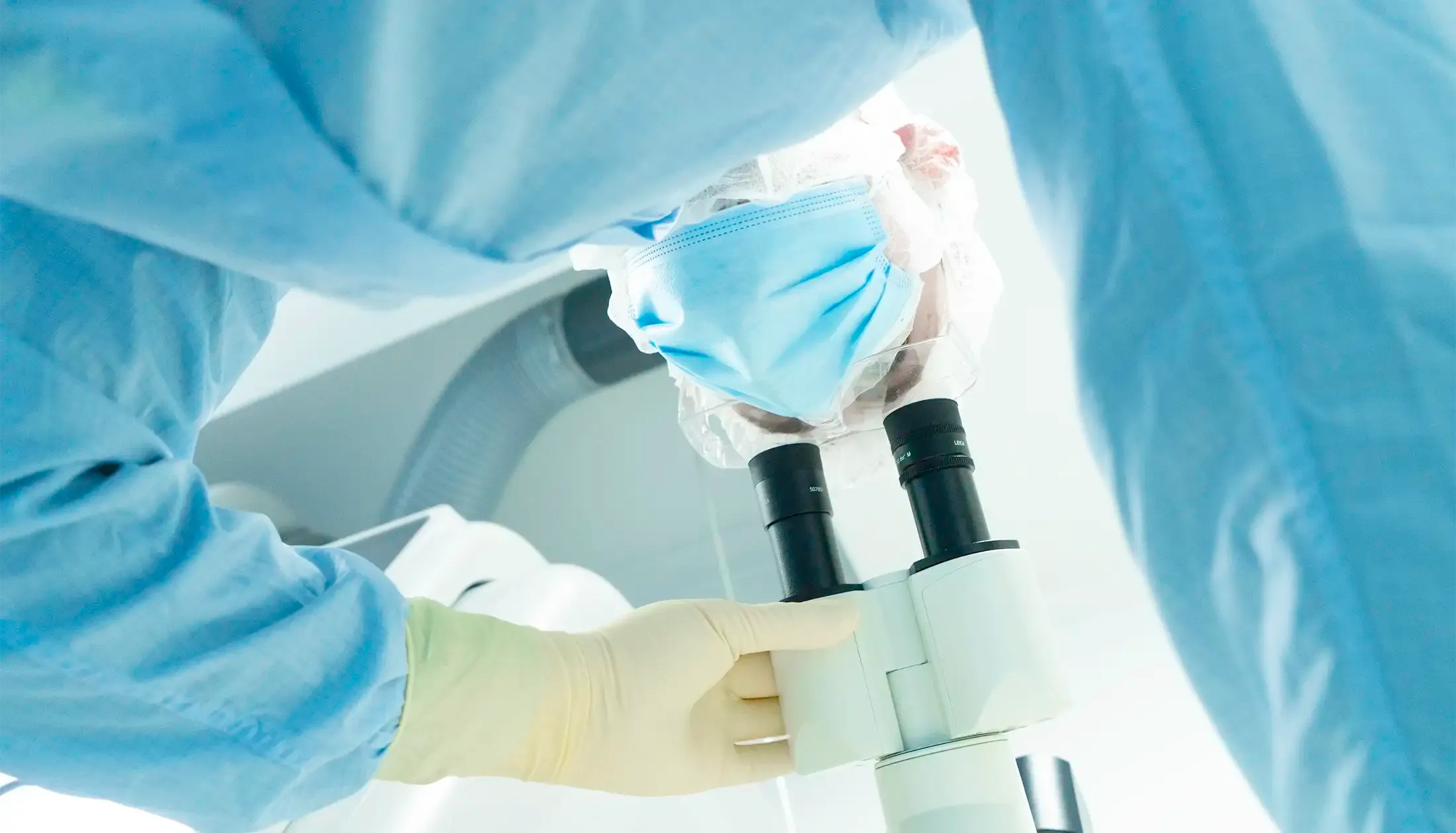 cleanroom scientist looking into a microscope