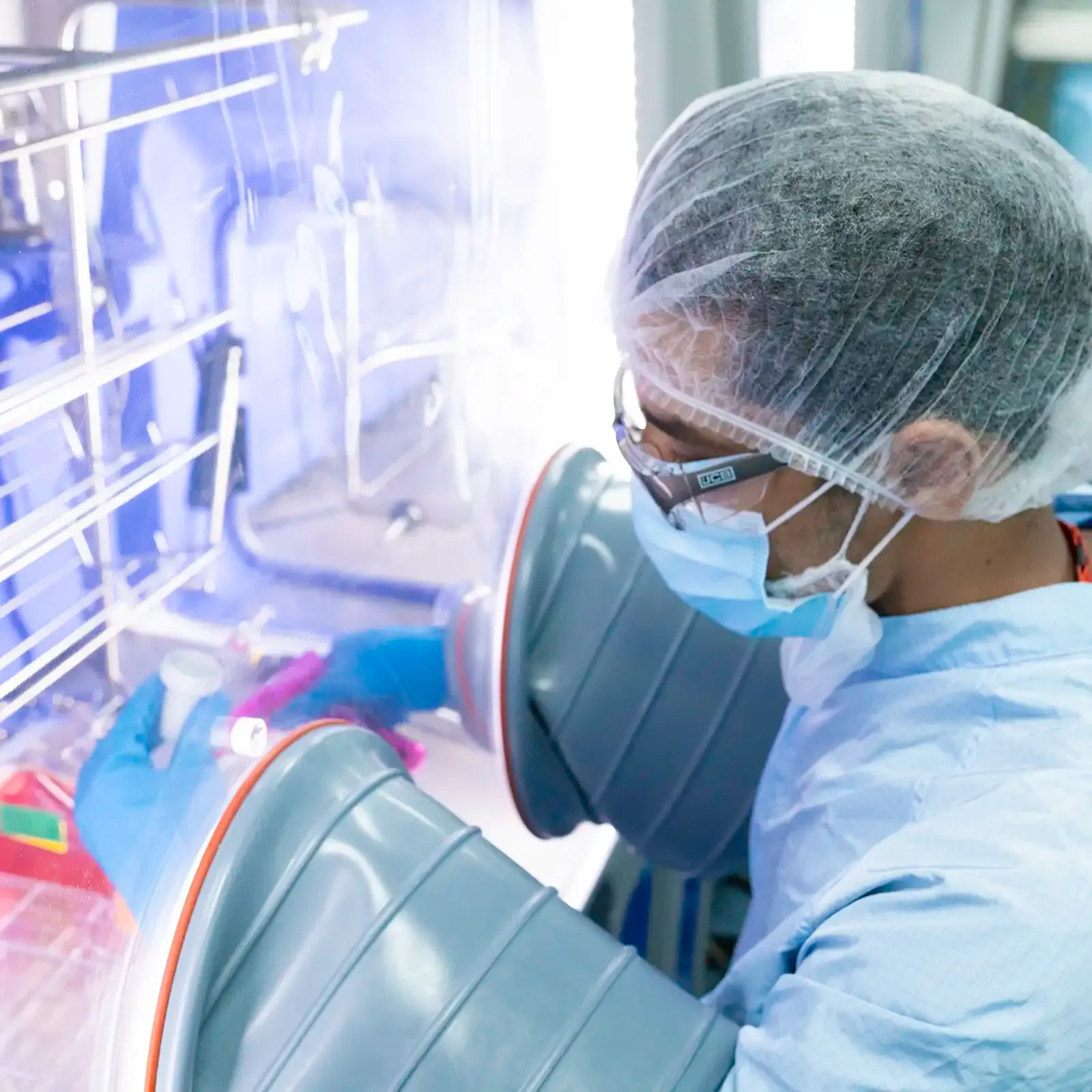 Scientist in a cleanroom laboratory with their arms inside a laboratory glovebox